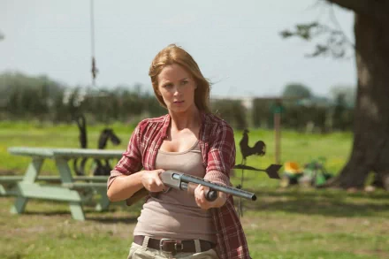 HD PC desktop wallpaper featuring a scene from the movie Looper with a woman holding a shotgun in a rural outdoor setting.