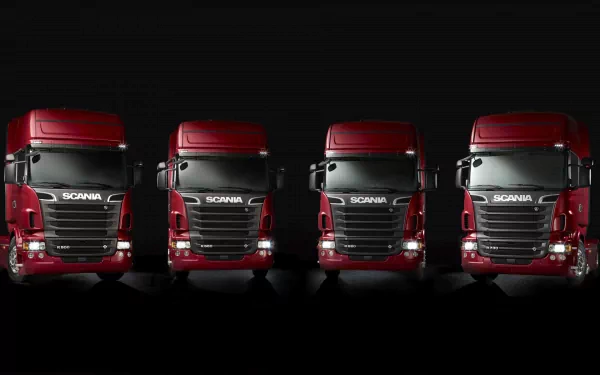 HD desktop wallpaper featuring four red Scania big rig semi trucks lined up against a dark background, highlighting the design of these powerful vehicles.