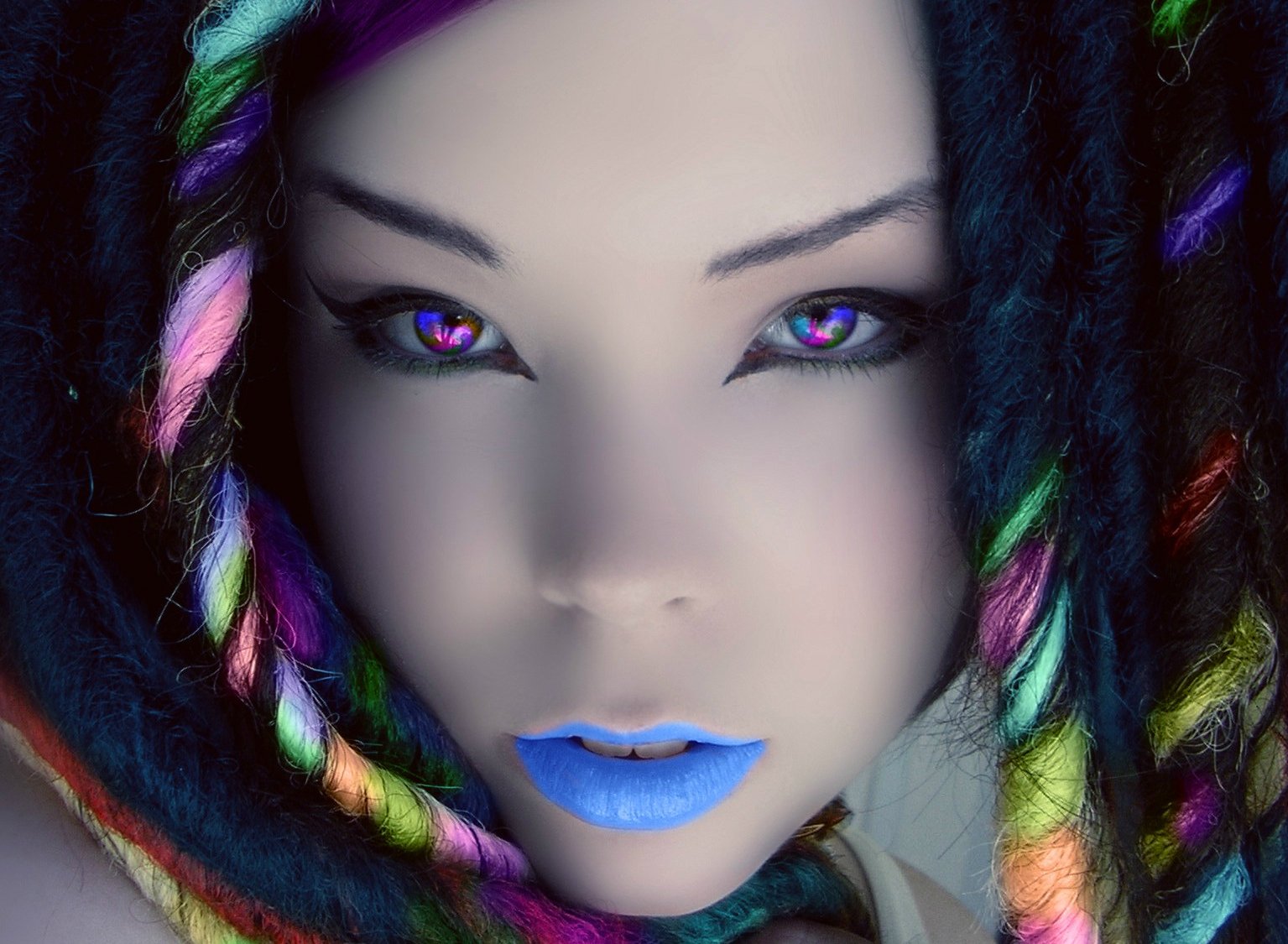 A captivating artistic portrait of a woman with colorful dreadlocks and striking blue lips, featuring vibrant rainbow tones. This HD wallpaper showcases a unique and bold aesthetic.