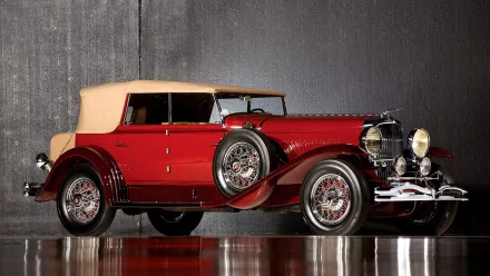 HD PC desktop wallpaper featuring a classic red Duesenberg Model J vintage vehicle with beige soft top, set against a textured gray background.