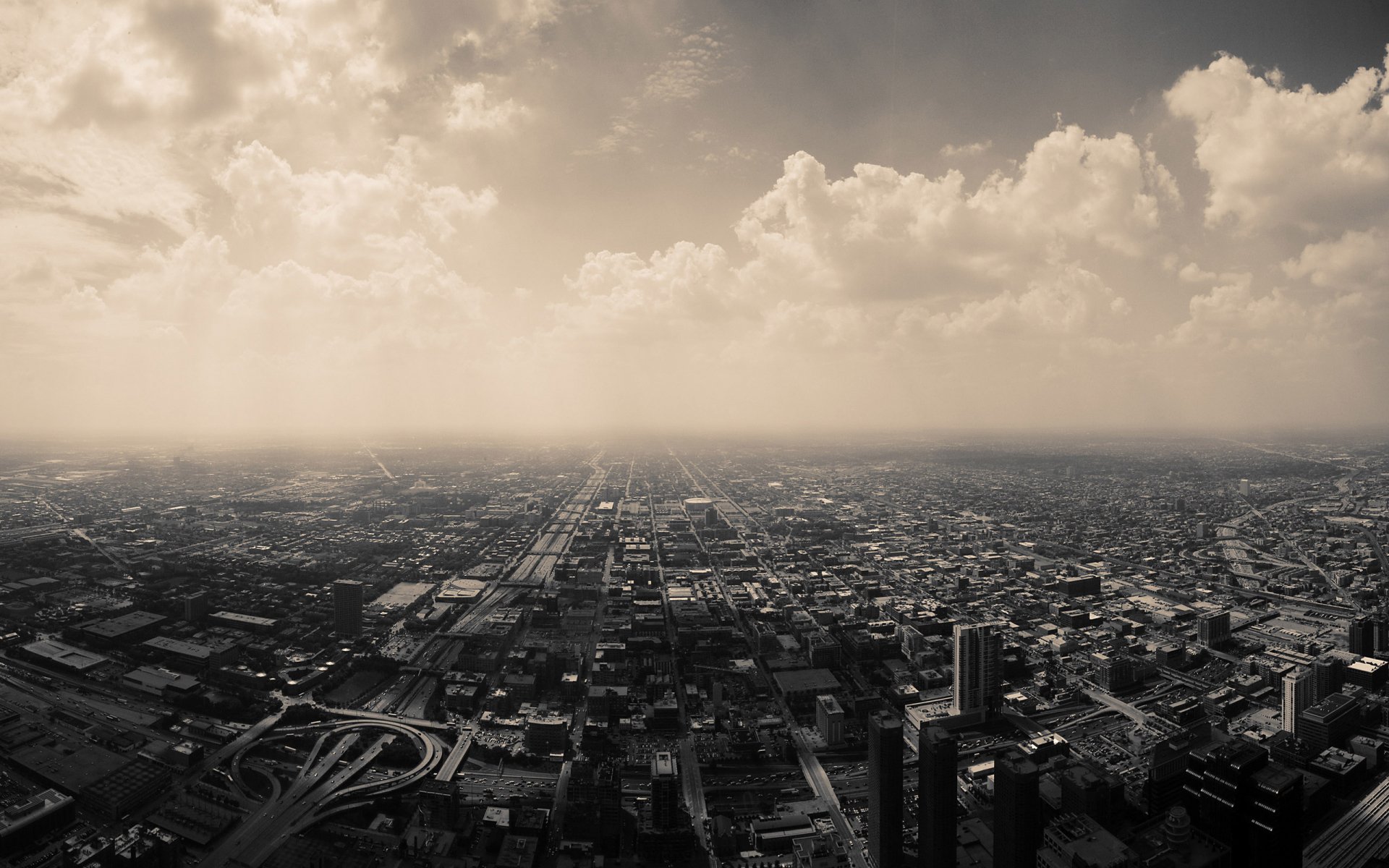 A vast, man-made cityscape under a dramatic, cloudy sky, captured in high definition as a PC desktop wallpaper and background.