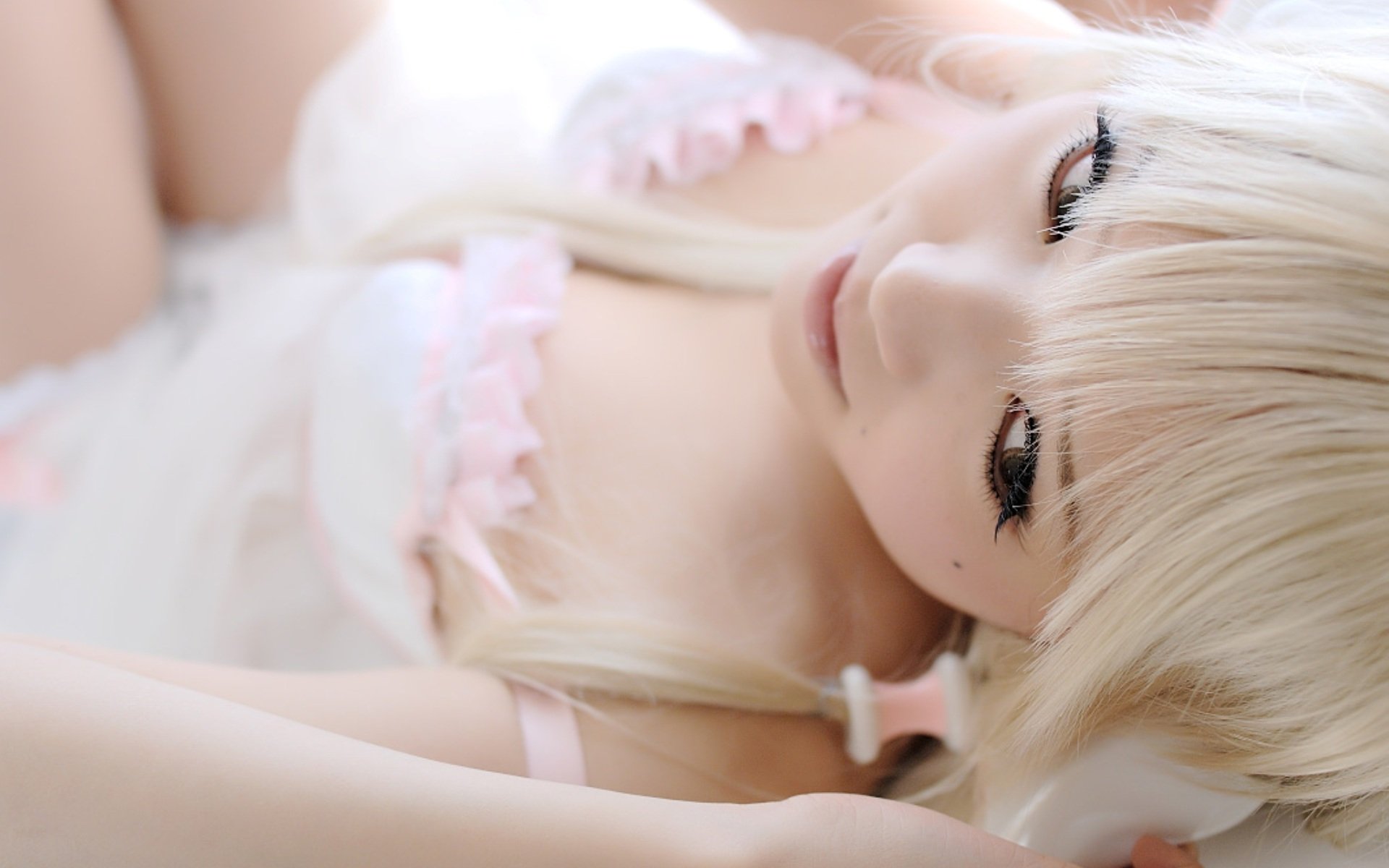 A woman in a Chobits cosplay, featuring Chi, gazes serenely. The image serves as a high-definition desktop wallpaper, highlighting her delicate features and soft colors.