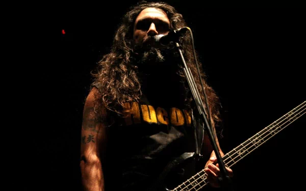 A striking HD desktop wallpaper featuring a musician with long hair performing passionately on stage, embodying the intense energy of Slayer's music.