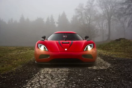 HD desktop wallpaper featuring a striking front view of a red Koenigsegg Agera, illuminated headlights and foggy forest background creating an atmospheric scene.