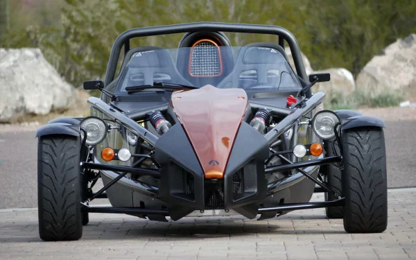 Front view of an orange Ariel Atom vehicle with exposed chassis on pavement — HD PC desktop wallpaper background showcasing the open-wheel sports car.