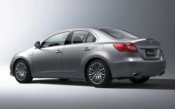 Silver Suzuki sedan shown from rear three-quarter view on a neutral gray backdrop — HD PC desktop wallpaper and background.