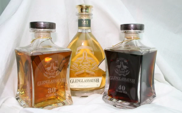 A high-definition desktop wallpaper showcasing three bottles of Glenglassaugh whisky, including aged selections of 30 and 40 years, elegantly displayed against a soft backdrop.