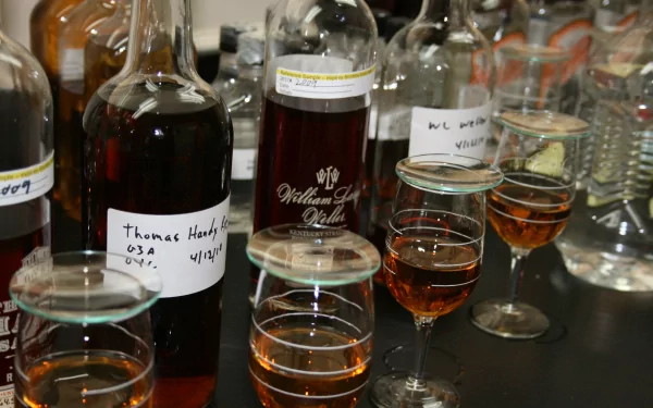 Food, whisky 4K Ultra HD PC desktop wallpaper: close-up of labeled whisky bottles and tasting glasses with amber pours arranged on a reflective tabletop.