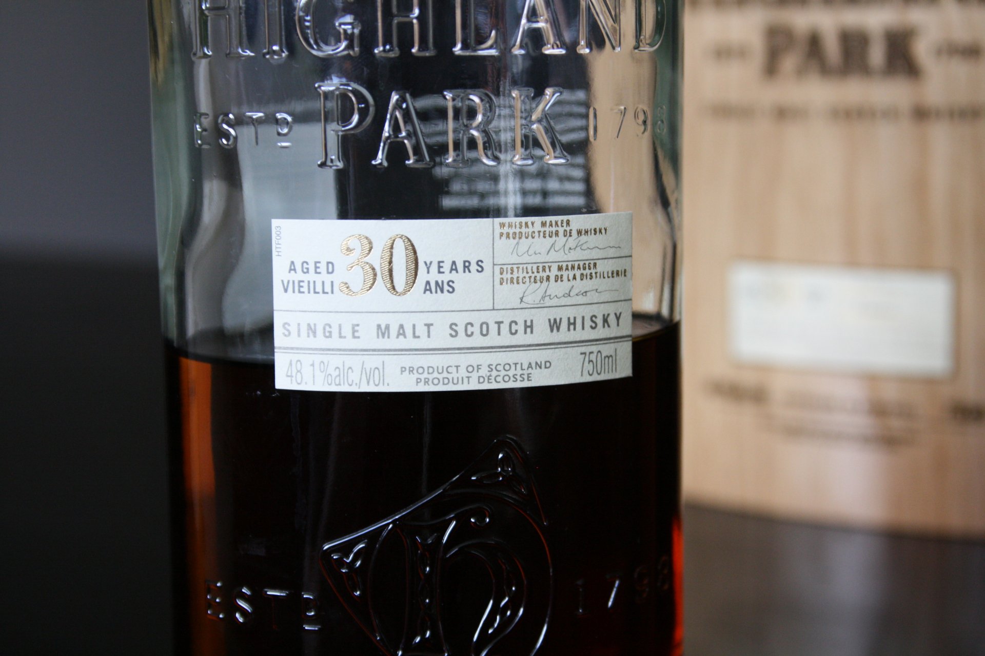 4K Ultra HD PC desktop wallpaper: close-up of a 30-year Highland Park single malt whisky bottle with a blurred wooden cask in the background — food & whisky theme.