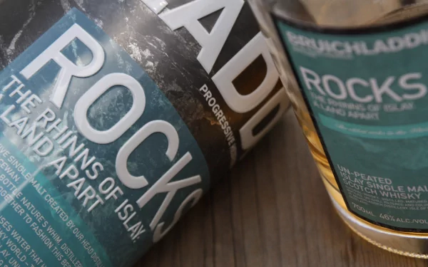 A close-up of Bruichladdich Rocks Scotch whisky bottles displays elegant labeling against a textured surface, showcasing the essence of Islay malt and fine spirits.