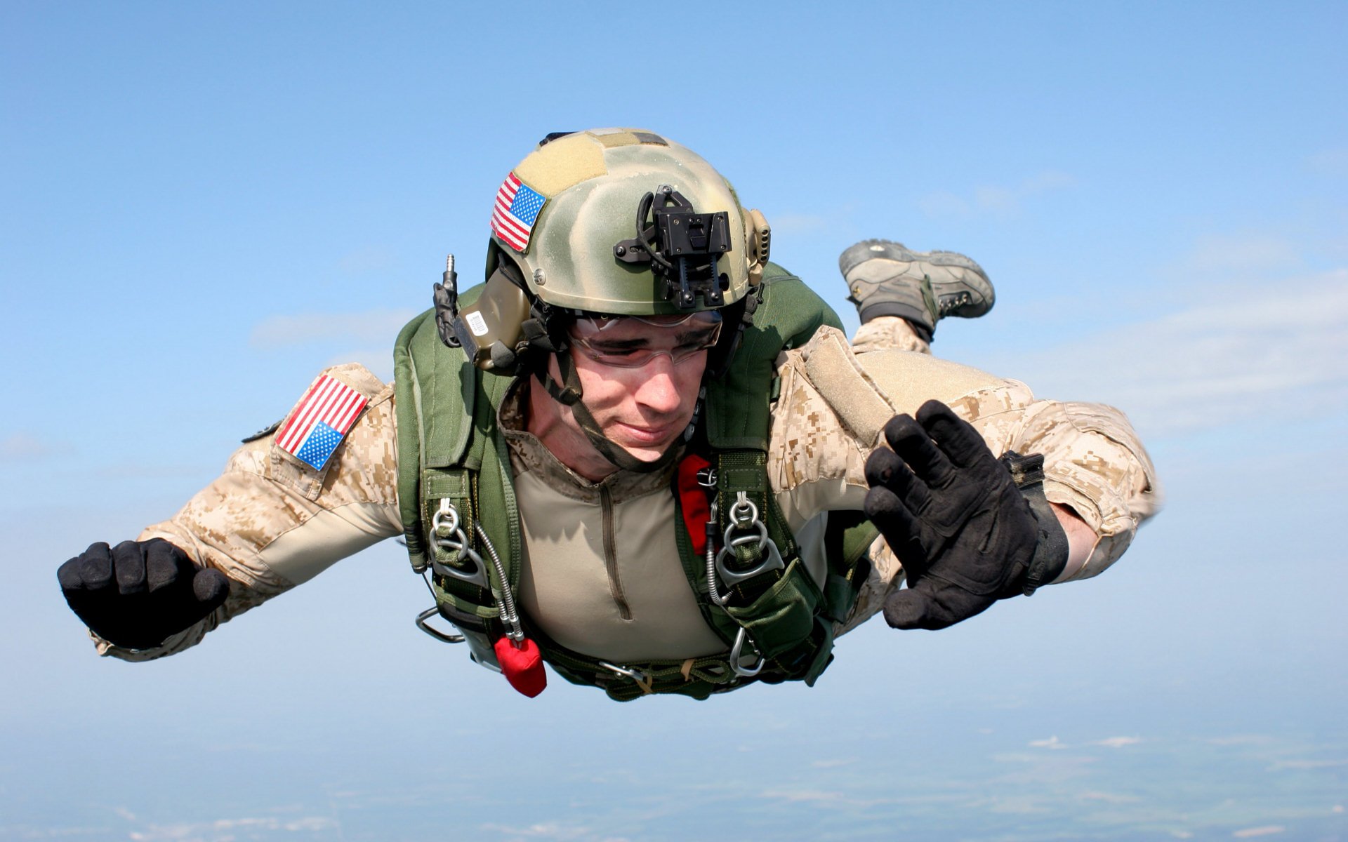 A military paratrooper descends through the sky, equipped with a weapon and wearing a helmet with gear, showcasing the adrenaline of parachuting in a stunning HD wallpaper.