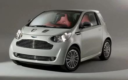 Silver 2011 Aston Martin 260 Cygnet compact car with red leather interior, studio-lit HD PC desktop wallpaper.