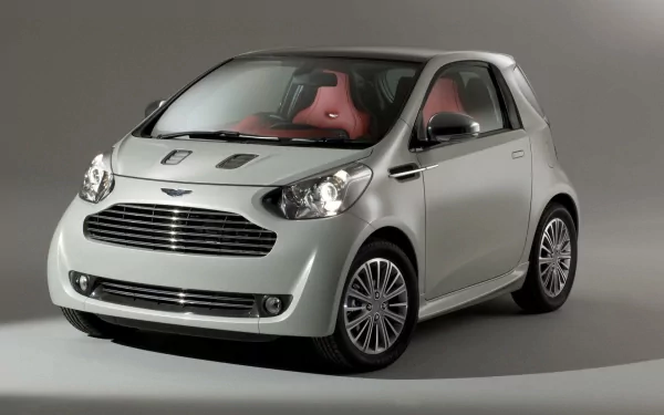 Silver 2011 Aston Martin 260 Cygnet compact car with red leather interior, studio-lit HD PC desktop wallpaper.