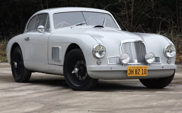 HD PC desktop wallpaper of a classic white Aston Martin DB2 parked on a concrete surface with a natural background.