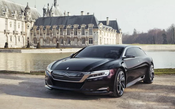 HD PC desktop wallpaper showing a sleek black Citroën vehicle coupe parked by a French château beside reflective water.