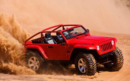 A vibrant red Jeep drives through sandy terrain, kicking up dust. This HD desktop wallpaper captures the rugged adventure spirit and high performance of the vehicle.
