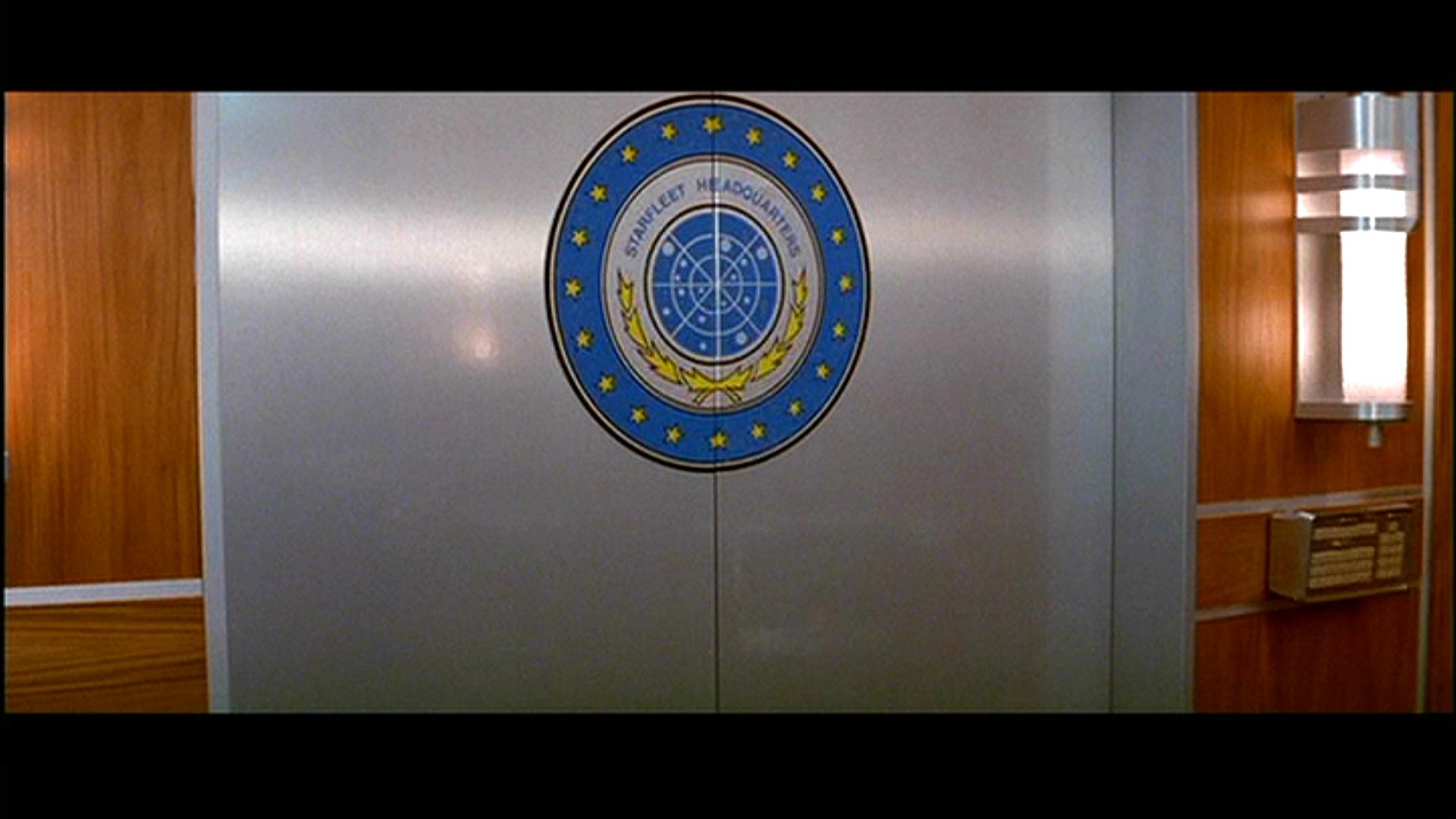 HD wallpaper featuring the emblem of Starfleet Command from Star Trek III: The Search for Spock, set against a sleek, modern interior backdrop.