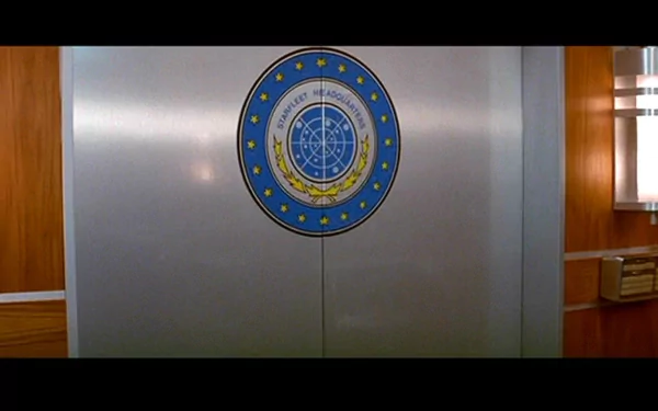 HD wallpaper featuring the emblem of Starfleet Command from Star Trek III: The Search for Spock, set against a sleek, modern interior backdrop.