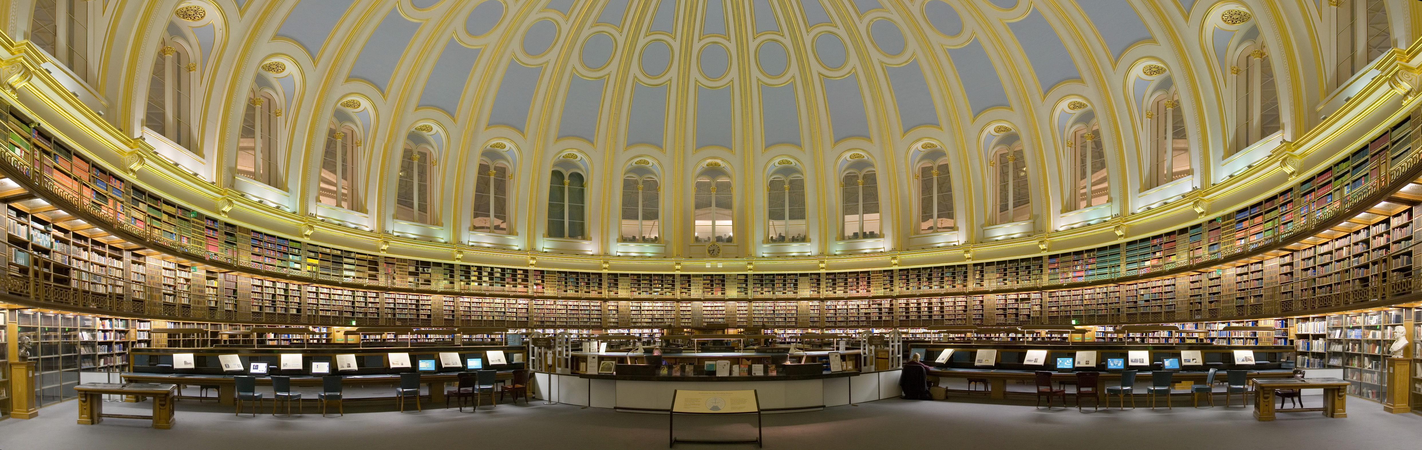 British Museum Reading Room with round tables, bookshelves, and a glass dome ceiling.