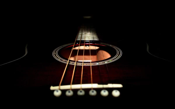 HD desktop wallpaper featuring a close-up view of an acoustic guitar against a black background, emphasizing the strings and soundhole in a dim, atmospheric lighting.