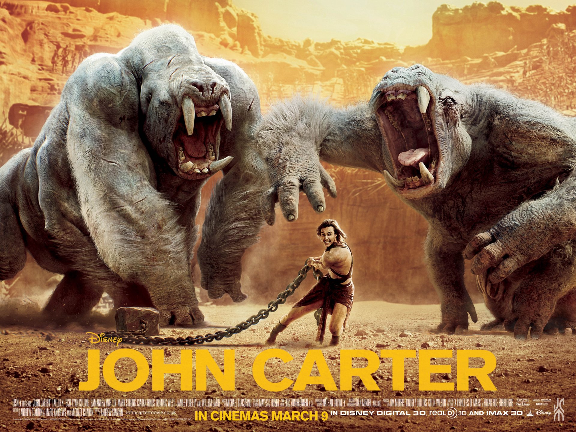 HD PC wallpaper: John Carter movie scene—hero chained between two towering, snarling monsters in a sunlit desert canyon.