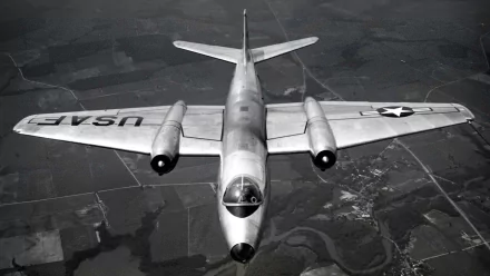 HD desktop wallpaper showing a vintage military aircraft in flight with USAF markings over a rural landscape.