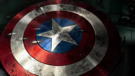 A close-up of Captain America's iconic shield, featuring its red, white, and blue design, set against a dark background, embodying the spirit of the Avengers movie.