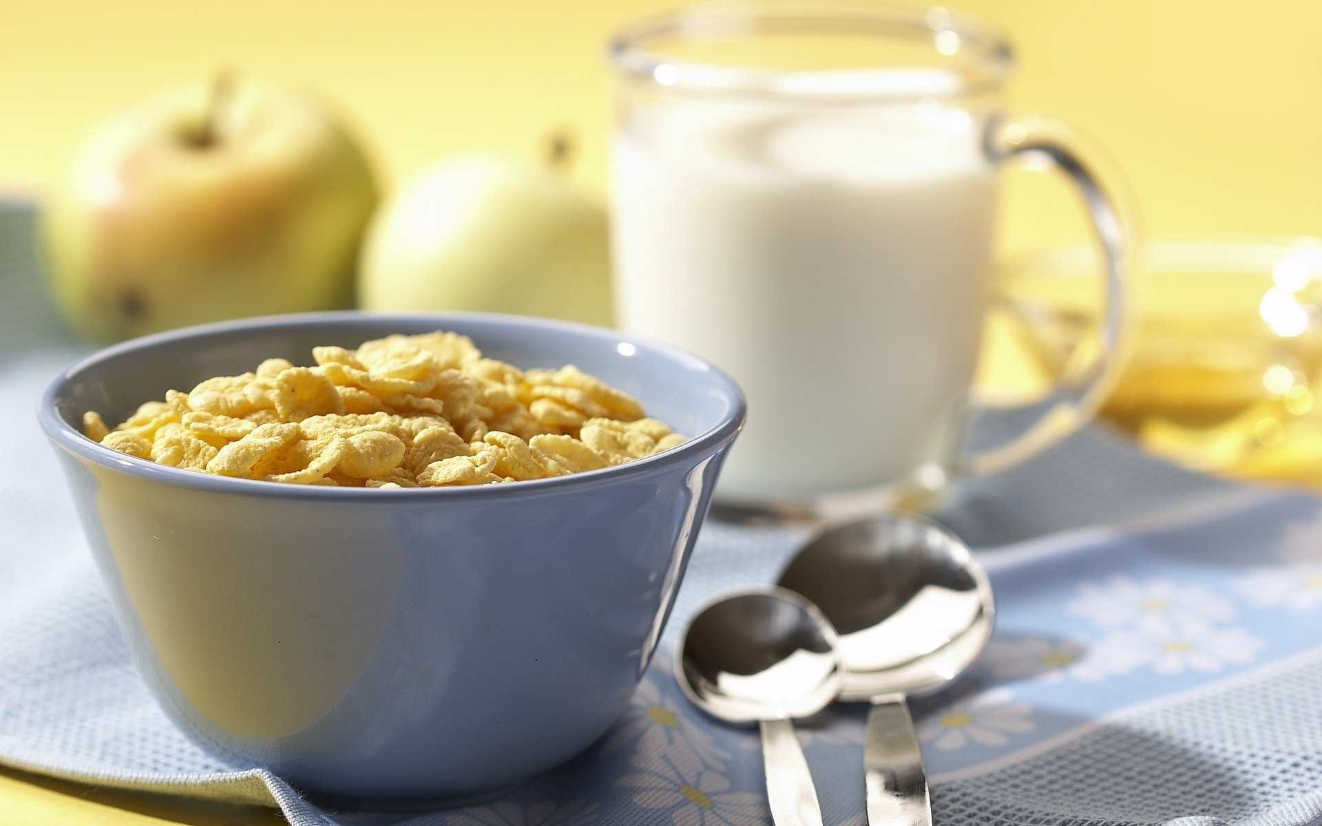 HD PC desktop wallpaper of cereal and milk: a bowl with milk pitcher, two spoons and apples on a blue cloth — breakfast food background.