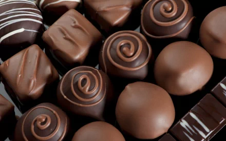 A close-up of assorted chocolate confections, showcasing a variety of shapes and designs. This vibrant image serves as a high-definition PC desktop wallpaper and background.