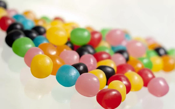 HD PC desktop wallpaper featuring colorful round candies in vibrant shades of yellow, green, pink, red, blue, and black scattered on a white surface.