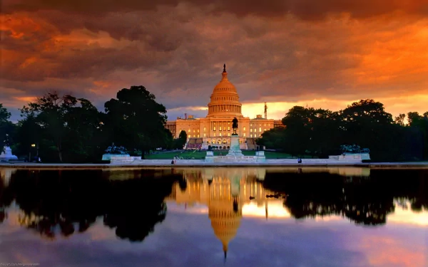 HD desktop wallpaper featuring the United States Capitol illuminated at sunset, with vibrant orange skies reflected in the water below.