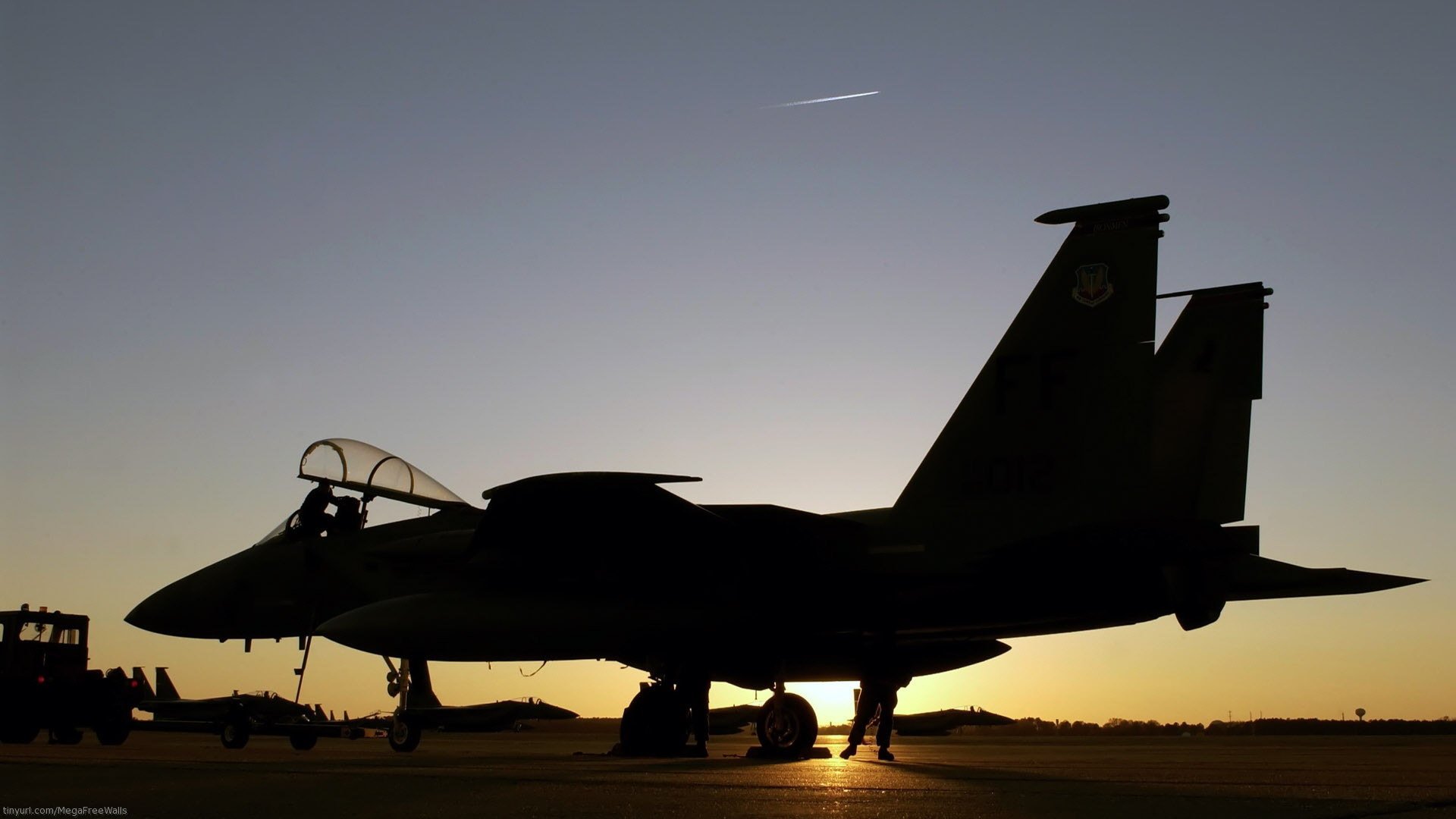 Silhouetted McDonnell Douglas F-15 Eagle military jet on the runway at dawn against a clear sky, captured in HD for a desktop wallpaper background.