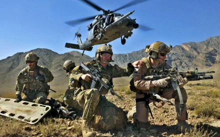 HD desktop wallpaper featuring a group of military soldiers in tactical gear with a helicopter flying overhead in a rugged mountainous desert landscape.