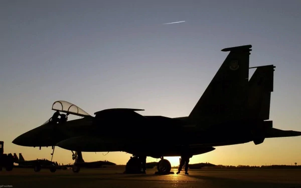 Silhouetted McDonnell Douglas F-15 Eagle military jet on the runway at dawn against a clear sky, captured in HD for a desktop wallpaper background.