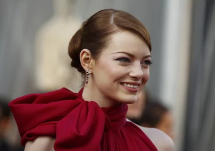 HD PC desktop wallpaper of celebrity Emma Stone smiling, wearing a stylish red outfit with an elegant updo hairstyle.