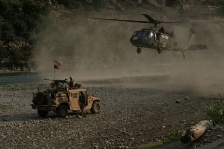 A Sikorsky UH-60 Black Hawk helicopter hovers above a military vehicle in a rugged, dusty landscape, depicted in a high-definition wallpaper tagged with USA and military themes.