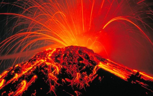 HD desktop wallpaper of an erupting volcano with vibrant lava and sparks lighting up the night sky. A stunning nature background capturing the raw power of a volcanic eruption.