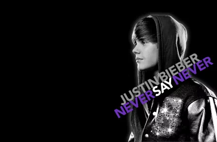 HD desktop wallpaper featuring Justin Bieber in a hoodie with the text Never Say Never prominently displayed. Black background with Bieber in grayscale. Tags: music, Justin Bieber.
