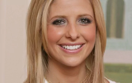 A smiling Sarah Michelle Gellar with long blonde hair and a bright expression, featured as an HD desktop wallpaper and background.