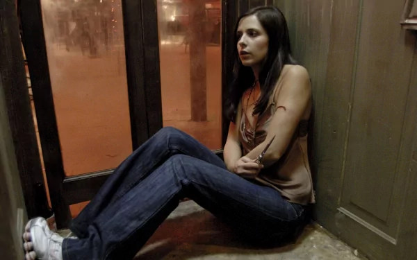 Sarah Michelle Gellar in a dramatic scene from the movie The Return (2006), sitting against a wall with a tense expression, captured in an HD desktop wallpaper.