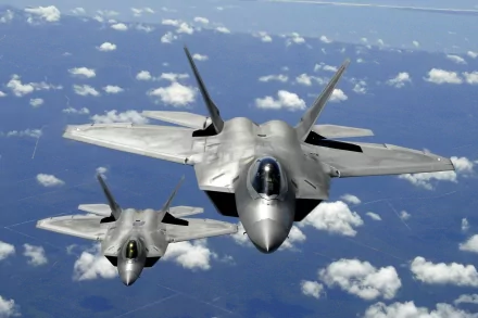 Two United States Air Force Lockheed Martin F-22 Raptors soar above the clouds in this HD desktop wallpaper and background.