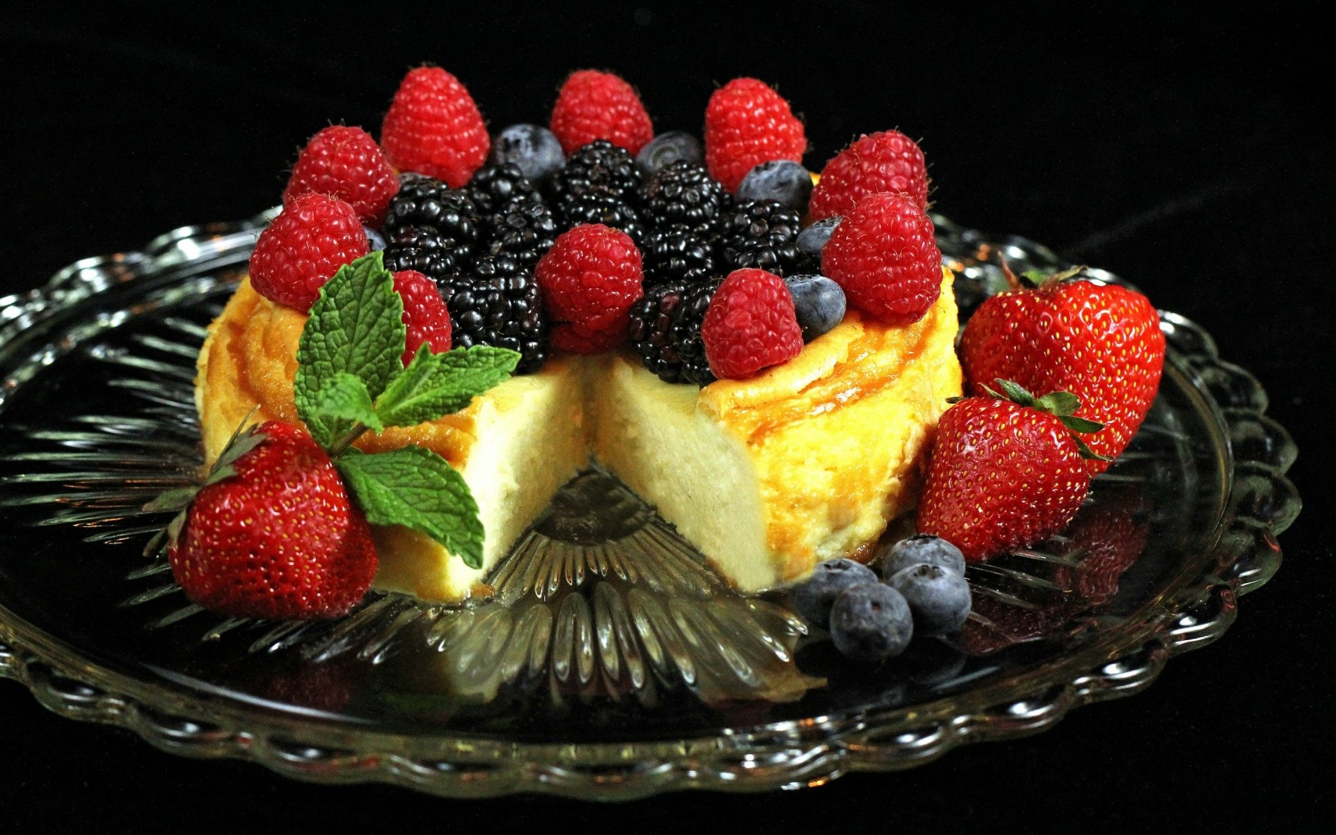 Food, cake: creamy cheesecake topped with raspberries, blackberries, strawberries and mint on a glass plate — 2K Quad HD PC desktop wallpaper background.