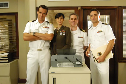 HD desktop wallpaper featuring the main cast of the TV show JAG dressed in military uniforms, standing together in an office setting.
