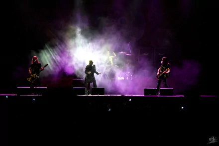 HD PC desktop wallpaper featuring the band Edguy performing live on stage with vibrant purple and white stage lighting and smoke effects.