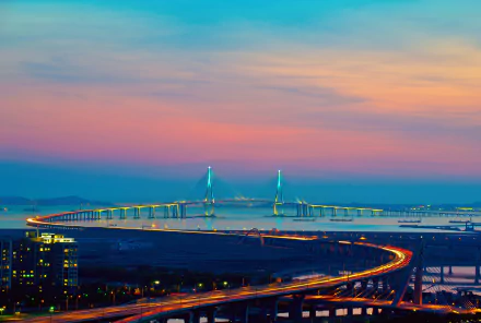 HD desktop wallpaper showcasing the man-made Incheon Bridge stretching across calm waters under a colorful sunset sky.
