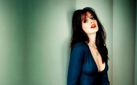 HD desktop wallpaper featuring celebrity Anne Hathaway posing against a greenish wall, wearing a blue dress with red lipstick.