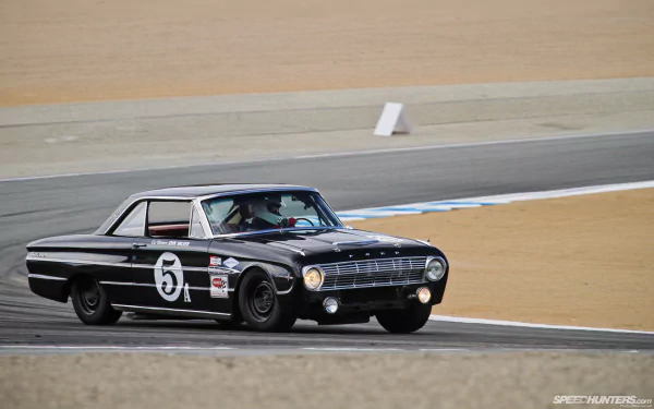 HD desktop wallpaper featuring a classic black Ford Falcon race car speeding on a track, showcasing its vintage design and racing decals.