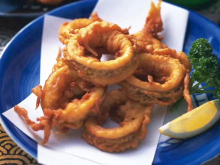 HD desktop wallpaper featuring a close-up of golden-brown grilled octopus rings served with lemon and parsley, highlighting seafood cuisine and octopus food.