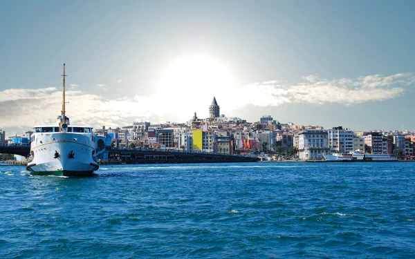 A stunning HD desktop wallpaper of Istanbul featuring a ship sailing on the blue waters with the cityscape and historic tower in the background under a bright sky.