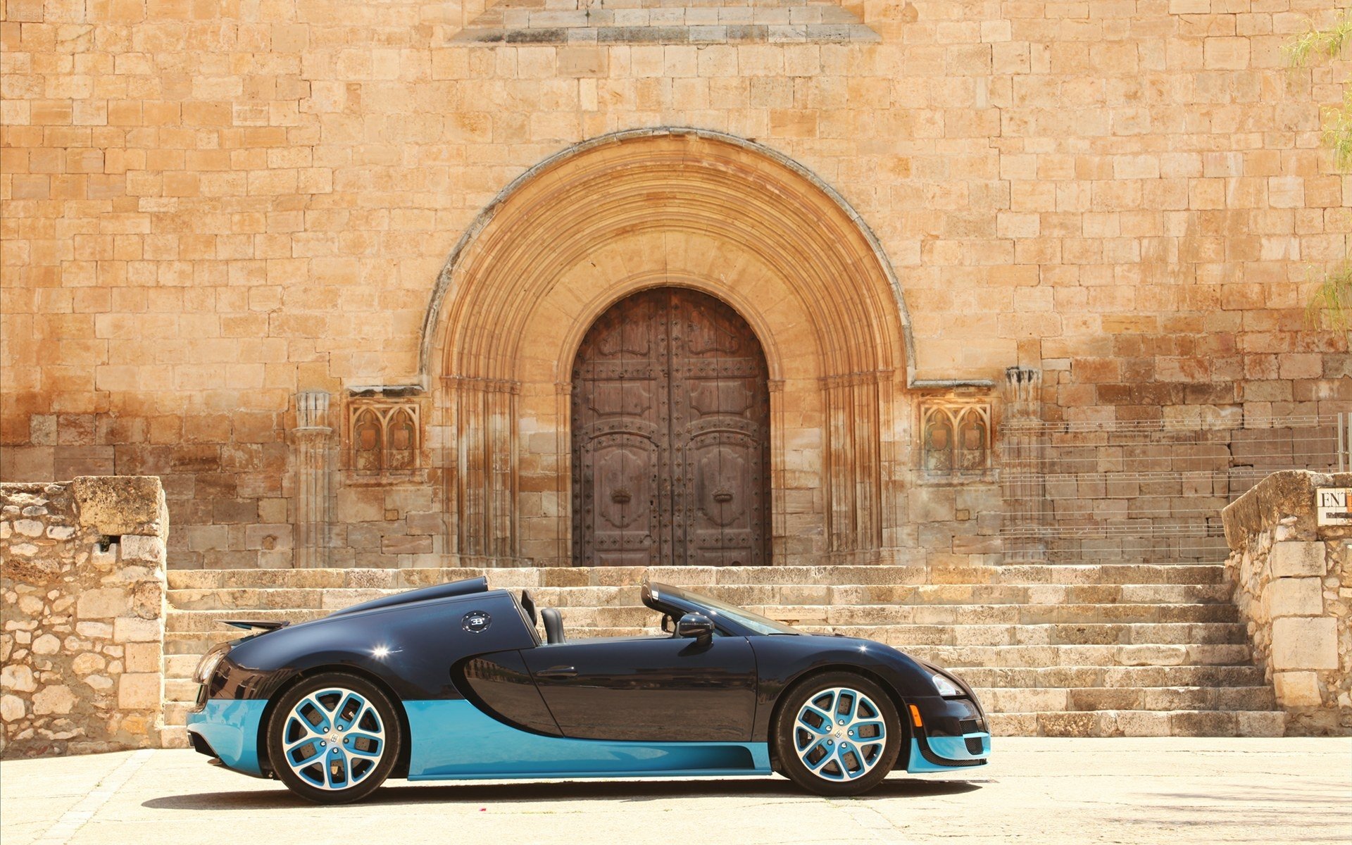 HD desktop wallpaper featuring a Bugatti Veyron parked in front of a historic stone building with arched doorway, showcasing the luxury vehicle’s sleek design.